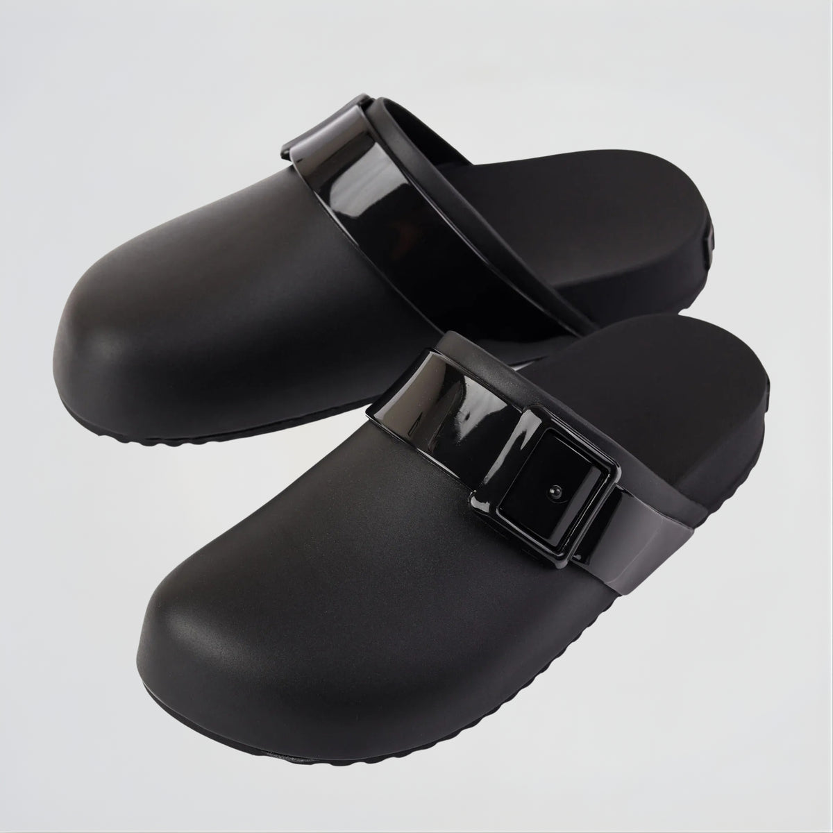Black clogs with buckles on a light gray background