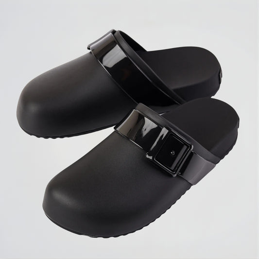 Black clogs with buckles on a light gray background