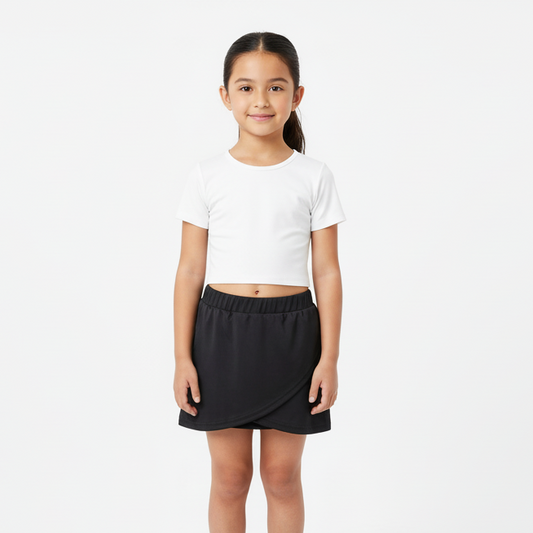 Young girl wearing a white crop top and black skirt on a white background
