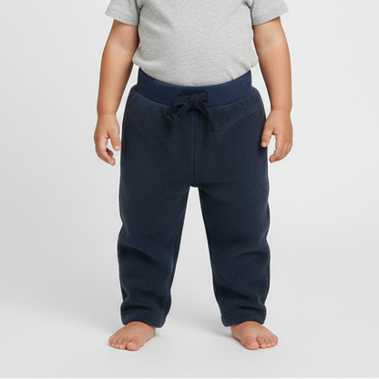 Child wearing a gray shirt and navy pants on a white background