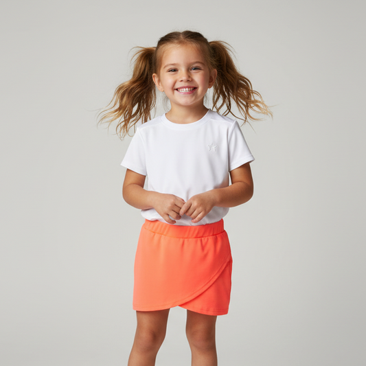Young girl wearing a white t-shirt and orange skirt on a plain background