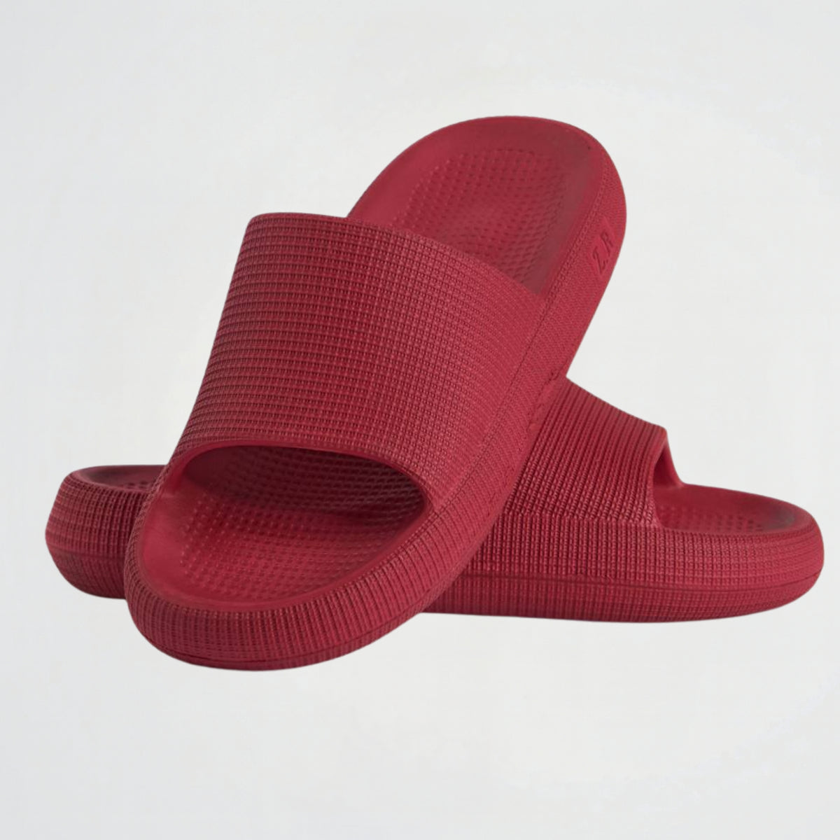 A pair of red slide sandals with a textured, ribbed strap and matching footbed, displayed on a clean white background.